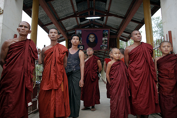 Buddhist monks try to get a glimpse of Aung San Suu Kyi visiting a polling station near their monastery in Kawhmu.
