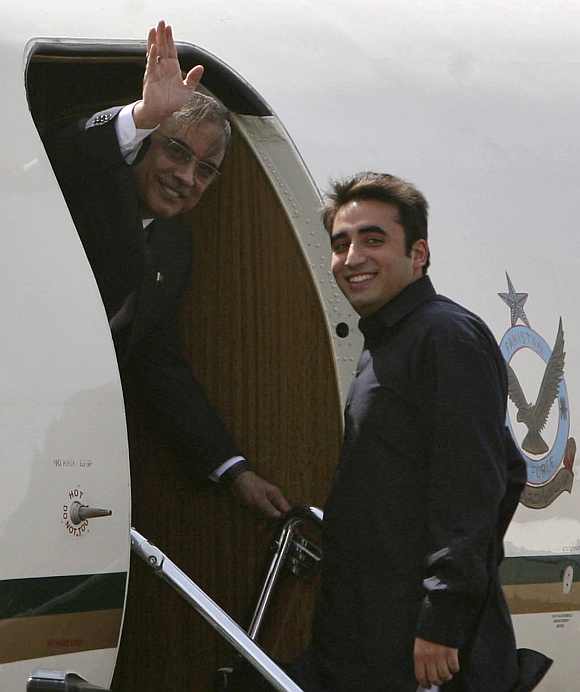 Pakistan's President Zardari waves as his son Bilawal looks on before they depart for Jaipur at the Delhi airport