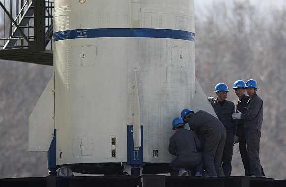 Engineers check the base of Unha-3 (Milky Way 3) rocket sitting on a launch pad at the West Sea Satellite Launch Site