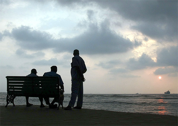 Private security guards sit on a seaside promenade after they evacuated beach-goers after the government announced a tsunami alert in Kochi