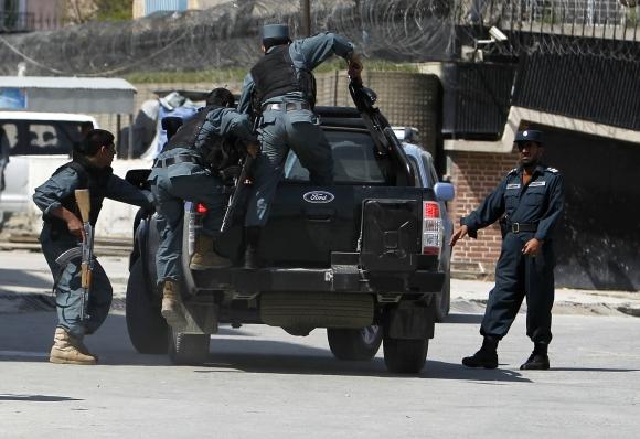 Armed Afghan police climb onto the back of a vehicle after gunmen launched multiple attacks in Kabul