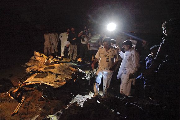 Aviation officials stand next to the wreckage of the Boeing 737 airliner