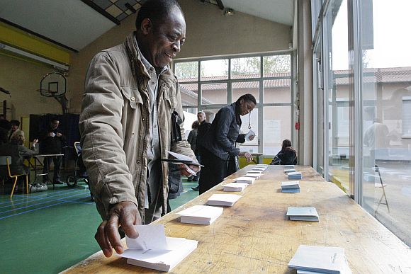 French citizens select ballots with the names of candidates at a polling station in the first round of the 2012 French presidential election in Vaulx-en-Veliln on Sunday