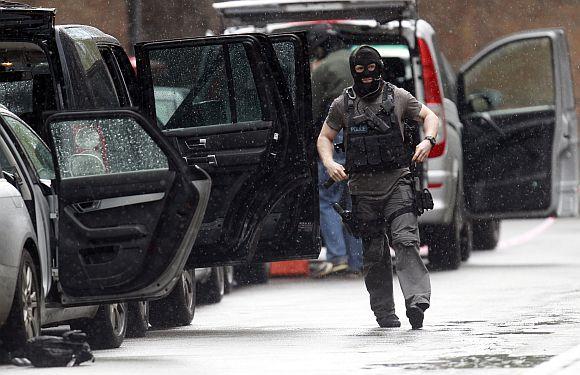 An armed police officer walks in Tottenham Court Road in central London where a man took four people as hostage and threatened to blow himself up, on Friday