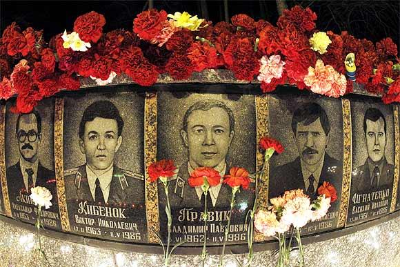 Flowers are placed on the memorial dedicated to firefighters and workers who died after the Chernobyl nuclear disaster during a night service near the Chernobyl plant in the city of Slavutych