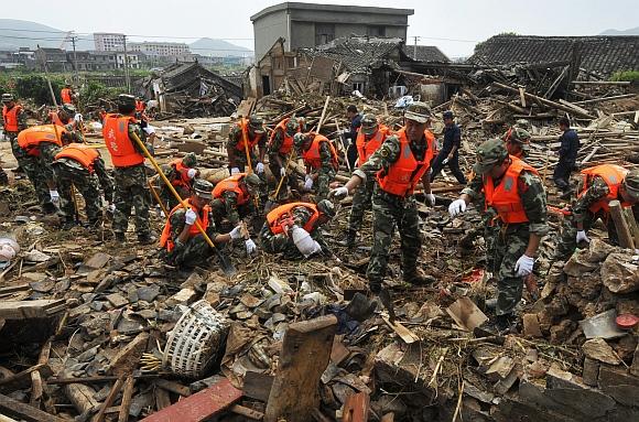 Paramilitary police officers search for victims amongst debris of destroyed houses after a flood caused by a dam breach in Daishan county, Zhejiang province