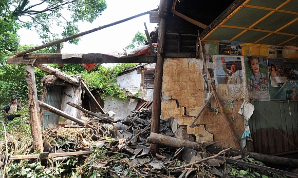 A man stands next to a damaged house after a flood caused by a dam breach in Daishan county, Zhejiang province