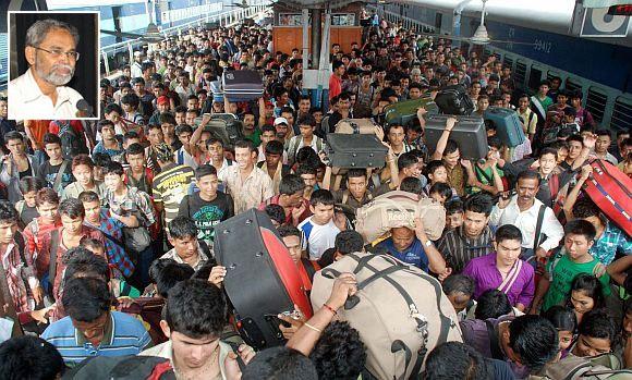 People rest while waiting for the train bound for Assam at a railway station