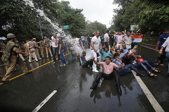 Hazare supporters shout slogans as police use water cannons to disperse them during a protest against corruption near the PM's residence