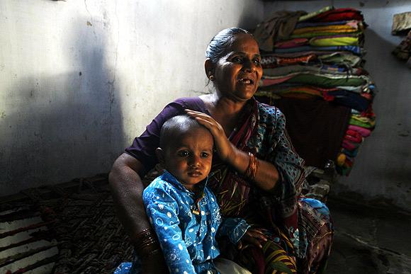 Hajira Sheikh, a riot survivor holds her grandson at her residence in the rebuilt Naroda Patiya