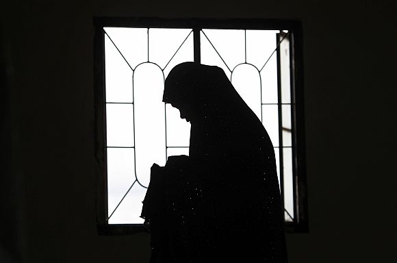 A Muslim woman is silhouetted as their community offers prayers of peace for recent violent protests and attacks in the Islamic world against the US, at a mosque in Marikina City