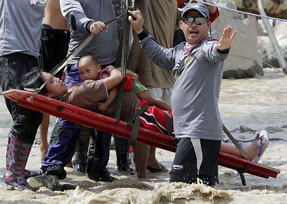 Rescuers evacuate a pregnant woman with her child after they survived flooding in New Bataan town in Compostela Valley in southern Philippines December 6, 2012. Rescuers found the six-months pregnant women from the other side of a river with her one-year-old son after escaping floods that swamped their house after Typhoon Bopha hit land on Tuesday in Compostela Valley