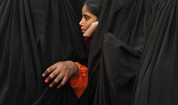 Veiled Muslim women with a girl stand at the airport to send off their relatives departing for Mecca, in Ahmedabad