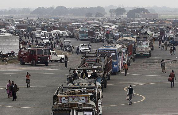 Polling officers sit atop a truck as they leave after collecting the electronic voting machines from a distribution centre ahead of the state assembly elections