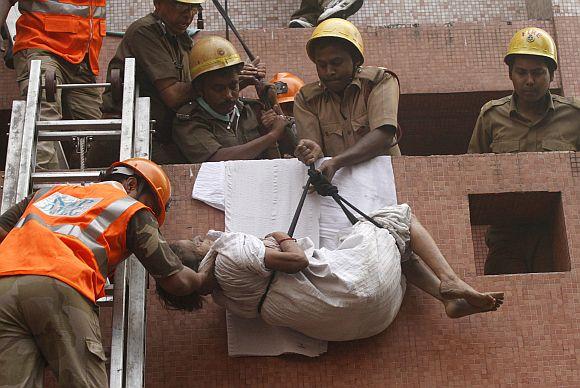 Firefighters evacuate a patient from AMRI hospital after it caught fire in Kolkata on December 9, 2011.