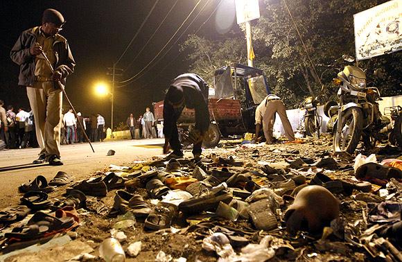 A man collects shoes left behind during a stampede in Junagadh district, in Gujarat