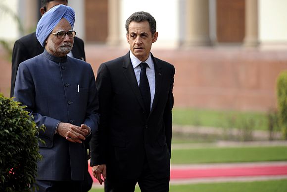 France's President Nicolas Sarkozy walks Prime Minister Manmohan Singh at Hyderabad House in New Delhi