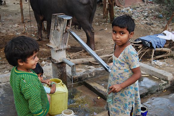 Children collect water from a hand pump in an urban slum in Agra, Uttar Pradesh