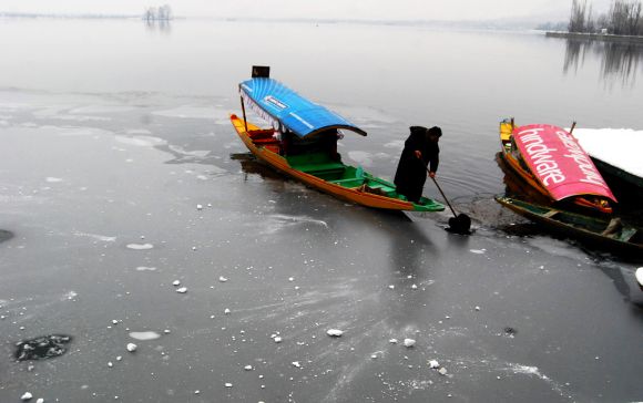 A boatman tries to steer his shikara through a semi-frozen Dal Lake in Srinagar