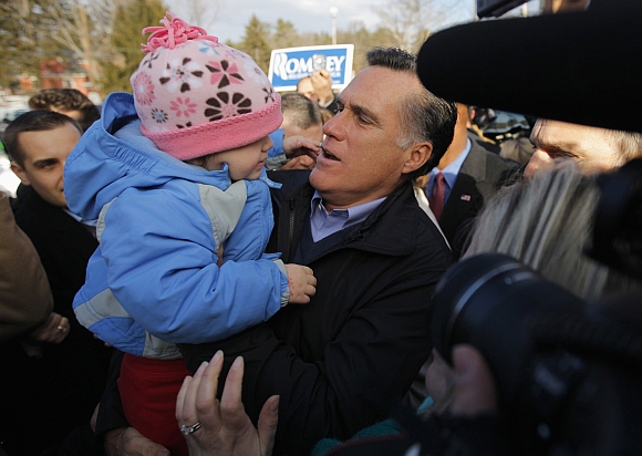 Romney holds a child while visiting a polling station in Manchester, New Hampshire