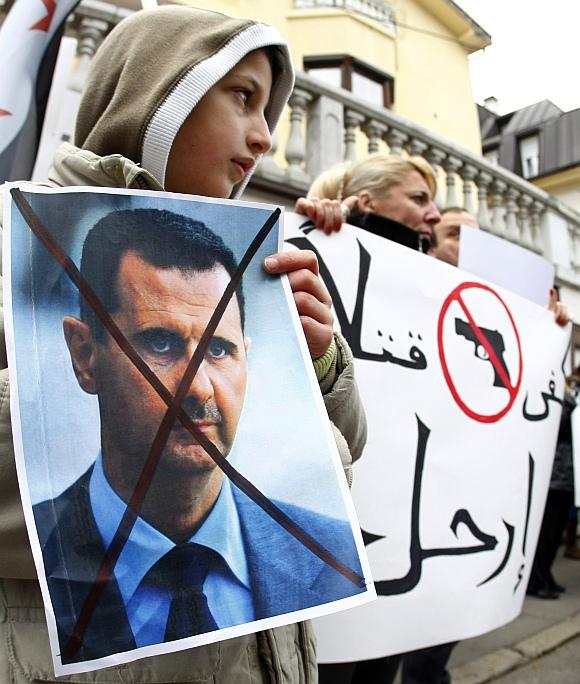 A Syrian holds a poster of Syrian President Bashar al-Assad during a protest against his regime