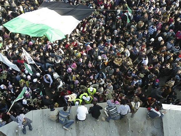 Arab League observers in yellow jackets are seen with anti-government protesters on the streets in Adlb