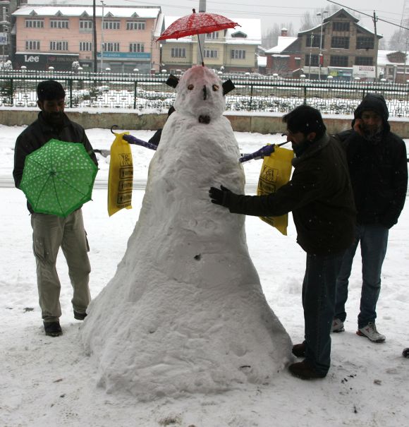 People stop to see a man make a snowman