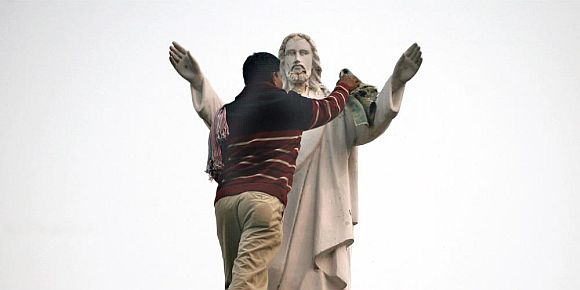 A worker cleans the statue of Jesus in New Delhi