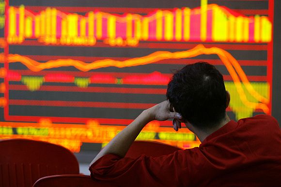 An investor looks at an electronic board showing stock information at a brokerage house in Wuhan, China