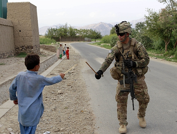 A US soldier uses a stick to play swords with a boy during a patrol in Shinwar district in Nangarhar, Afghanistan