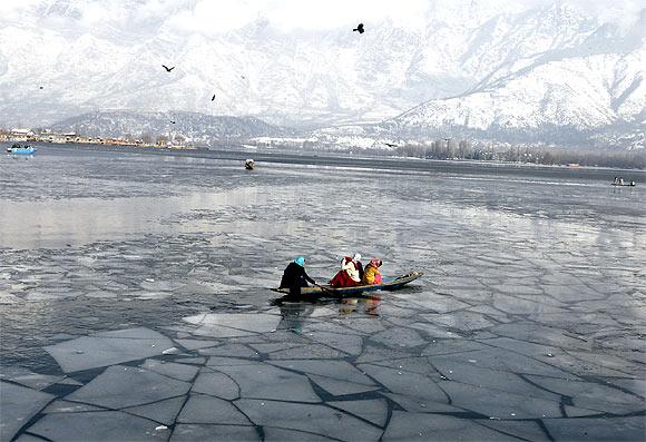 Kashmiri women row a boat at the frozen Dal Lake in Srinagar