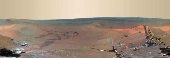 From fresh rover tracks to an impact crater blasted billions of years ago, a newly completed view from the panoramic camera on NASA's Mars Exploration Rover Opportunity shows the ruddy terrain around the outcrop where the long-lived explorer spent its most recent Martian winter