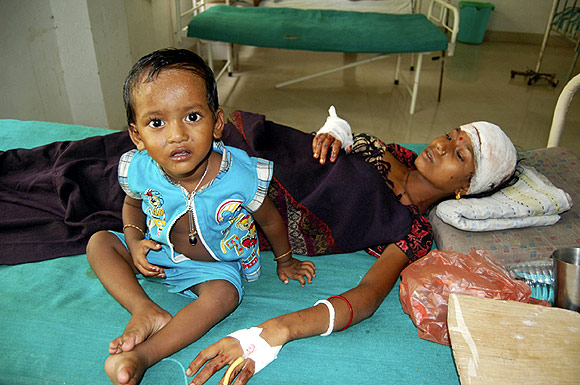 An injured local resident Prnima Das, 32, rests with her child in a hospital after violence near Kokorajhar town