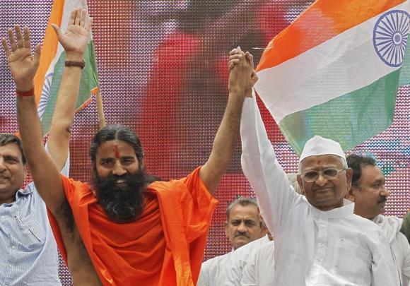 Swami Ramdev and activist Hazare raise their hands during their day-long hunger strike against corruption in New Delhi