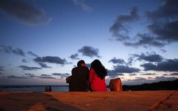 A couple sits along the seafront promenade