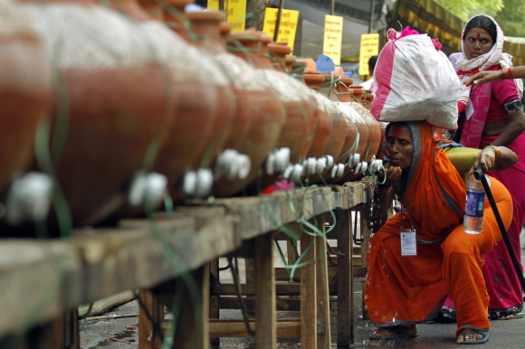 A woman drinks water stored in an earthen pitcher along a roadside in New Delhi