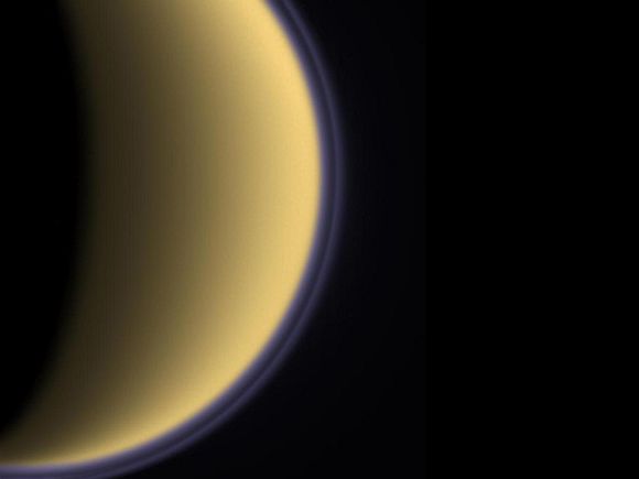 Encircled in purple stratospheric haze, Titan appears as a softly glowing sphere in this colourised image