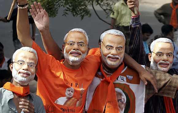 Supporters of the BJP wear masks of Modi in Ahmedabad