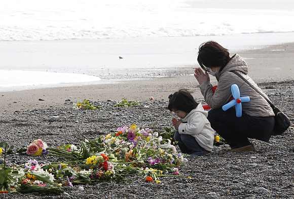 A mother and her daughter offer prayers for victims of the March 11, 2011 earthquake and tsunami disaster at a seaside which was damaged by the disaster in Iwaki, Fukushima prefecture to mark the first anniversary of the earthquake and tsunami that killed thousands and set off a nuclear crisis