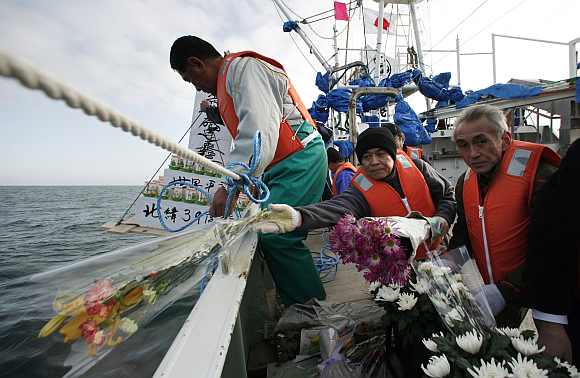 Fishermen throw flowers and lanterns into the sea as they offer prayers to victims of the March 11, 2011 earthquake and tsunami in Ofunato
