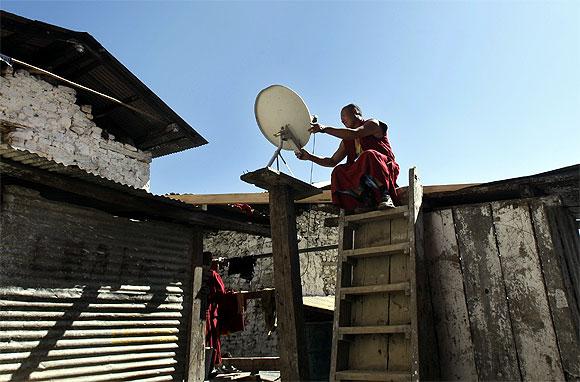 A Buddhist monk fixes a television satellite dish at a monastery in Tawang in Arunachal Pradesh