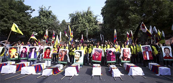 Tibetan exiles holding portraits of protesters, who were killed during demonstrations in China's Sichuan province, stand behind mock coffins during a protest in New Delhi