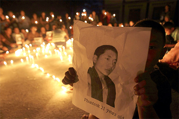A Tibetan child holds a portrait of Tibetan monk Phuntsog who killed himself through self-immolation
