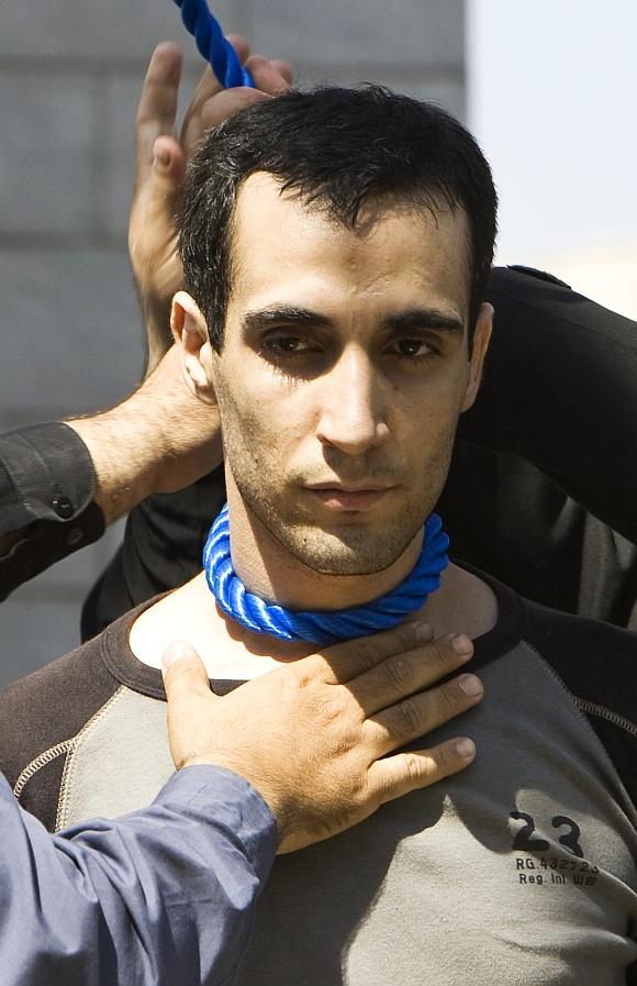 Iranian policemen prepare Majid Kavousifar for his execution by hanging in Tehran. Iran hanged Majid and Hossein, the killers of a judge who had jailed several reformist dissidents, before a crowd of hundreds of people