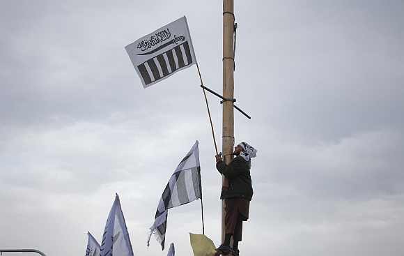 A supporter of the Jamaat-ud-Dawa Islamic organisation stands on a poll while holding his party flag during an anti-US and NATO demonstration in Islamabad on March 27