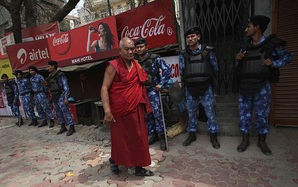 A Tibetan exile walks past Rapid Action Force (RAF) personnel at Majnu Ka Tila, a Tibetan refugee camp, in New Delhi