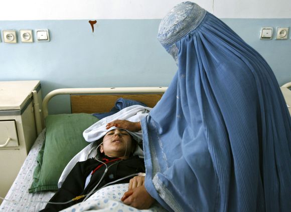 An Afghan woman clad in a burqa, checks on her daughter in a hospital in Charikar city
