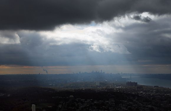 Rays of sunshine stream through the clouds with the Manhattan skyline