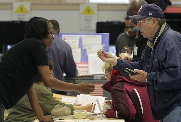 A man presents his voter ID card to a poll worker to vote in the U.S. residential election at a displaced polling center in the Coney Island section of Brooklyn, New York