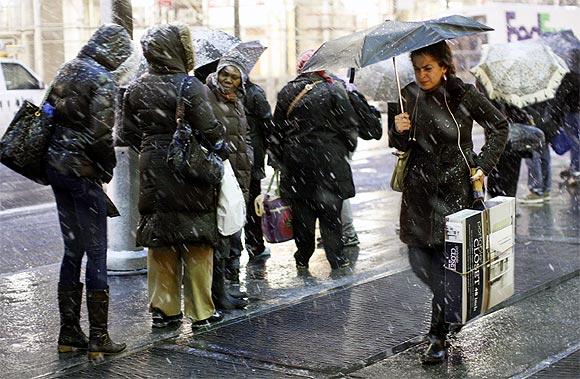 eople wait at a bus stop during a snow storm in New York on Wednesday